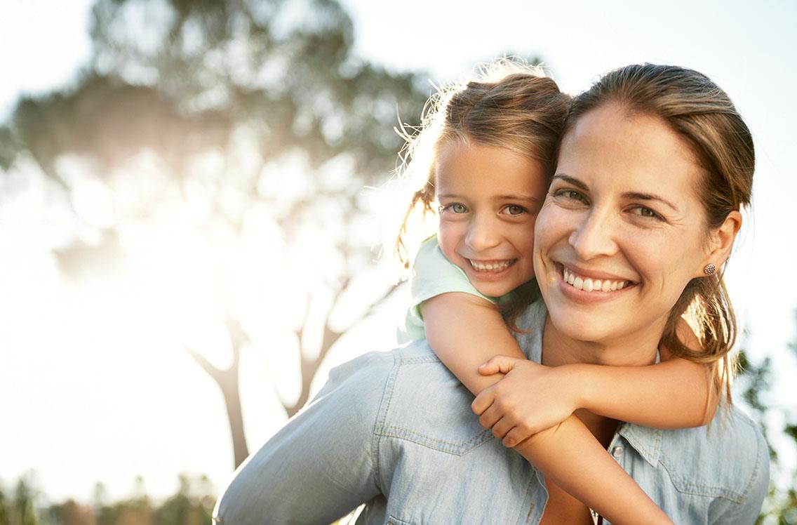 Mother and daughter smiling together outdoors
