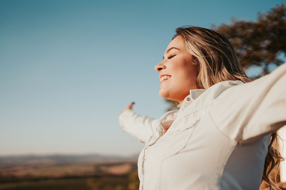 woman with outstretched arms at sunset