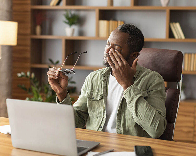 Tired man at computer from long COVID symptoms